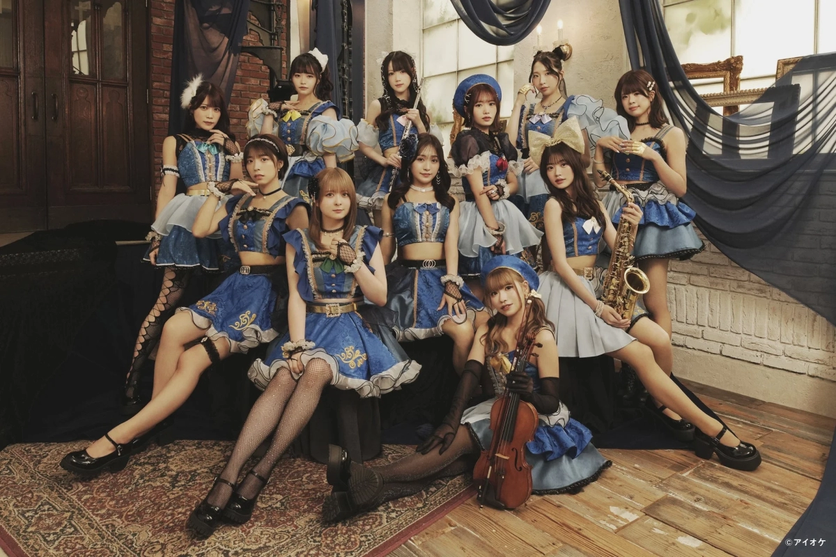 i-Okey members in elegant blue and white outfits posing with instruments on a dark stage