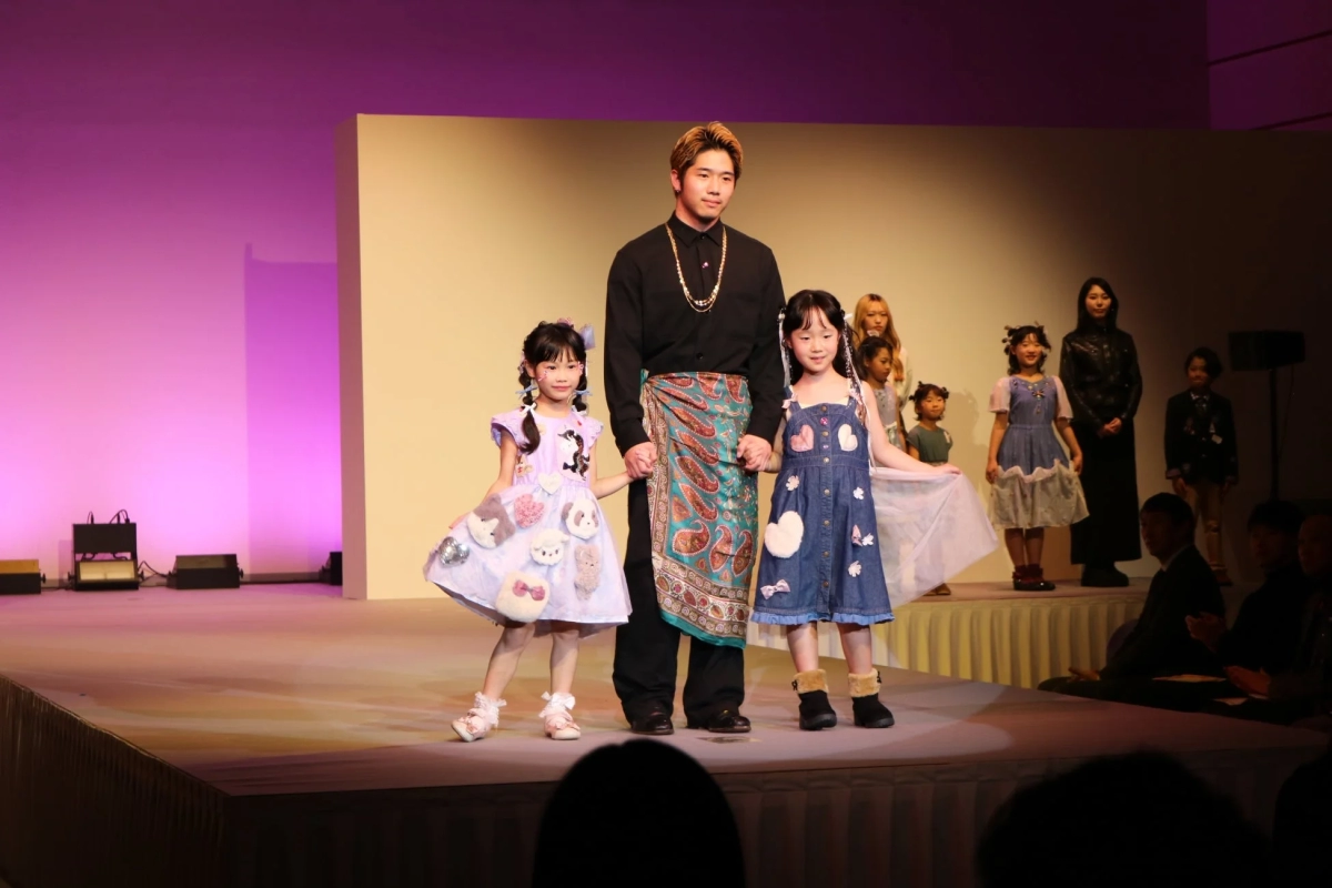 An adult model with two children posing on stage