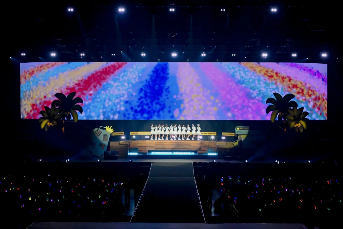 ≒JOY performing on a stage with a tropical themed backdrop