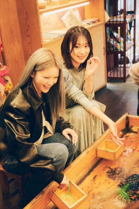 Two women concentrating on goldfish scooping