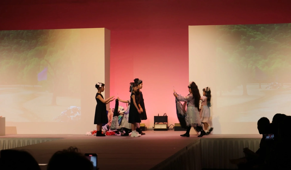 Girls on stage at the fashion show, holding garments