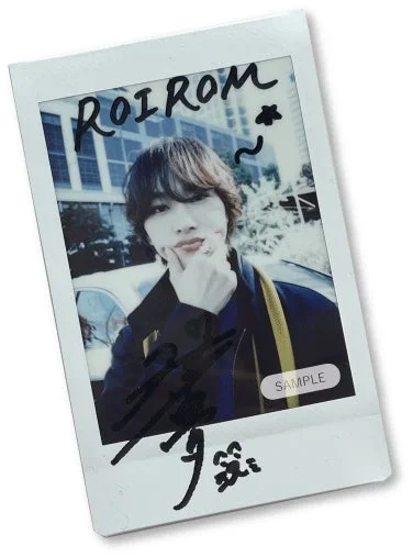 A polaroid photo of a young man posing, with a handwritten signature and "ROIROM ~ SAMPLE" text.
