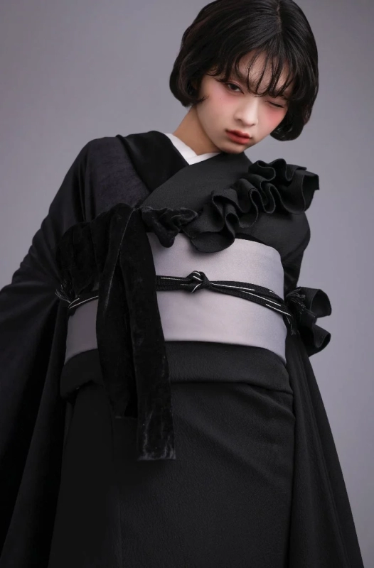A woman with short hair in a black kimono with modern ruffles