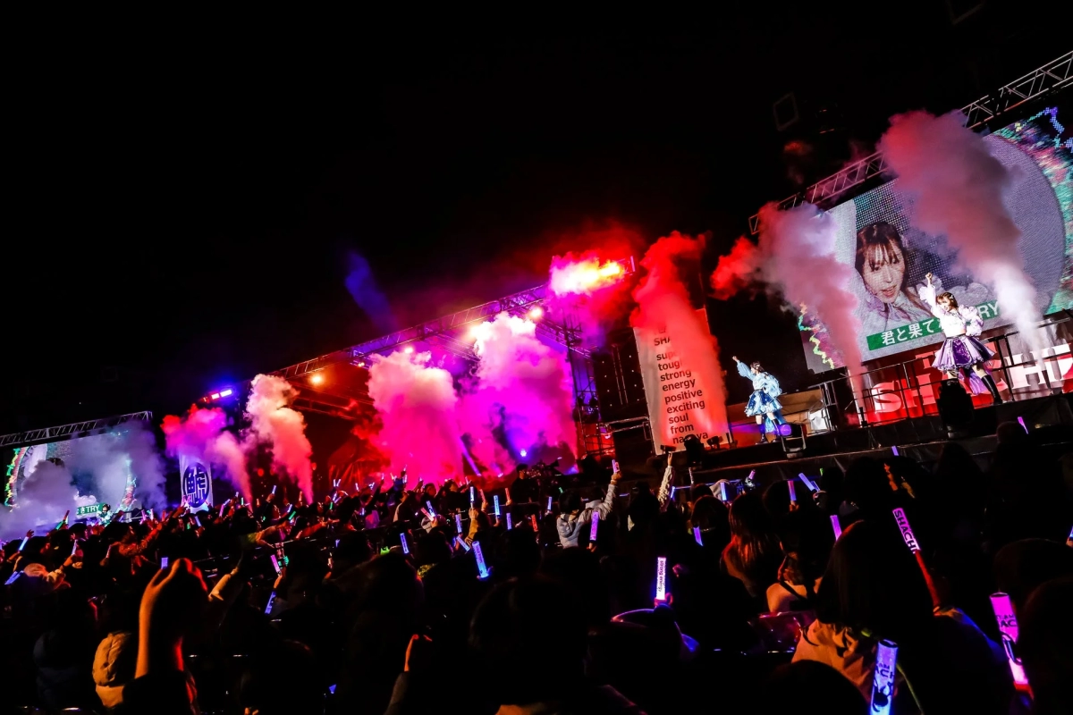 TEAM SHACHI on stage with colorful lighting and smoke