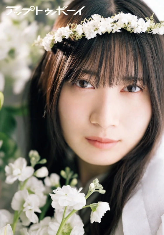 A young woman with a flower crown looking gently at the camera