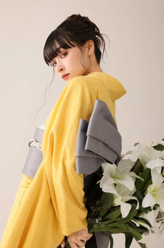 A woman in a yellow kimono holding white lilies