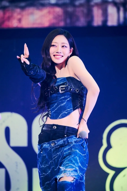 Female idol on stage with a microphone, pointing and smiling