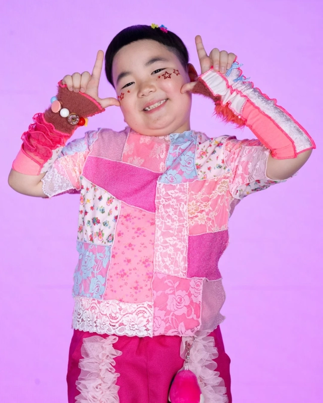 Otoha, a child in a pink patchwork and lace outfit, smiling