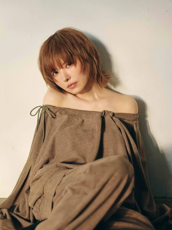 A woman with short hair wearing a brown off-shoulder top