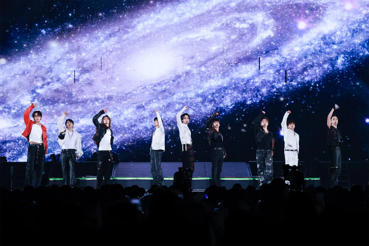 Male idol group performing on stage with a galaxy-themed background