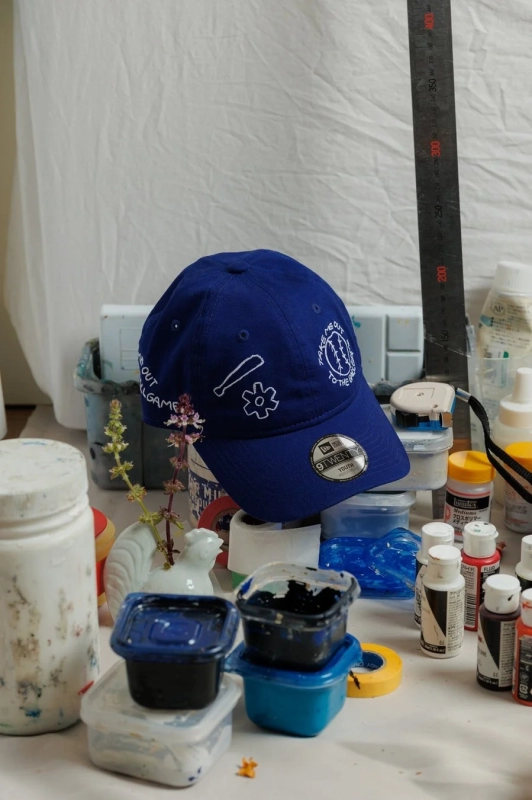Cap surrounded by art supplies