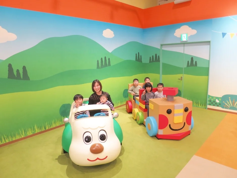 Kids and mother playing with toy cars in a colorful room