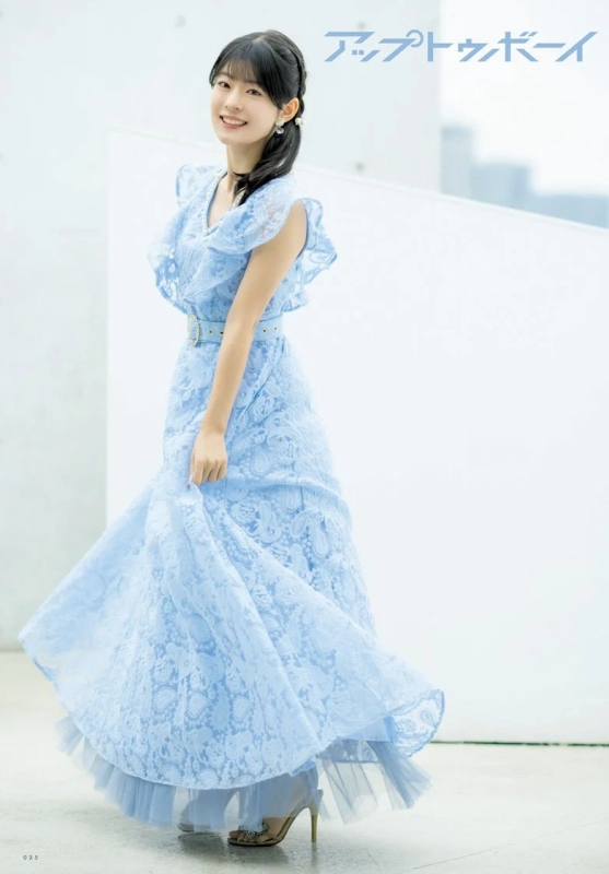 A young woman in a light blue lace long dress smiling outdoors