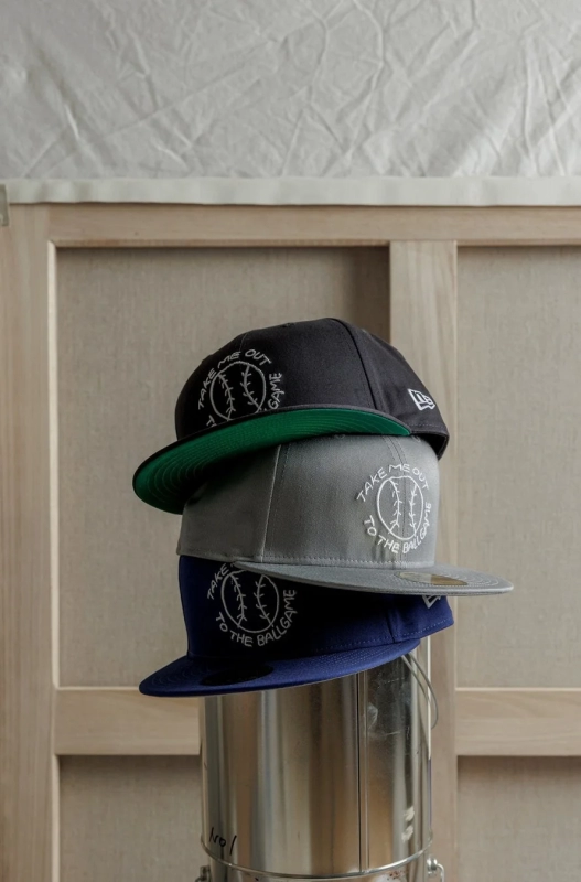 Stacked New Era caps with Izumida's artwork