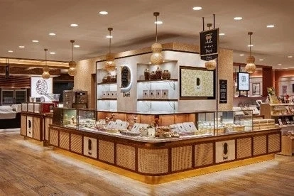 An image of a modern, bright sweets shop interior with various products displayed in a showcase, resembling a high-end donut store called 'Dali'.