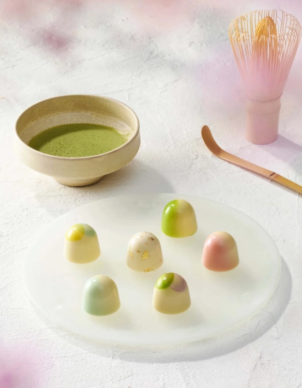 Colorful bonbon chocolates arranged on a white plate with matcha tea set