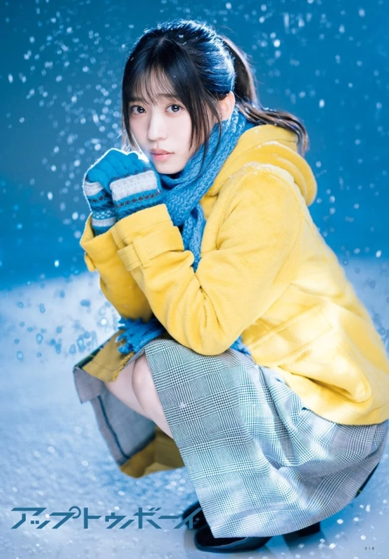 A young woman in a yellow coat and blue scarf in a snowy setting