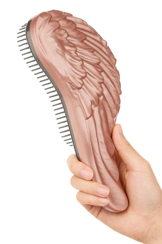 A hand holding a rose gold "angel wing" hair brush.