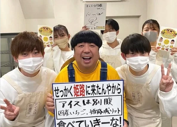 Group photo with "Ice wa Betsubara" sign, possibly from TV show appearance