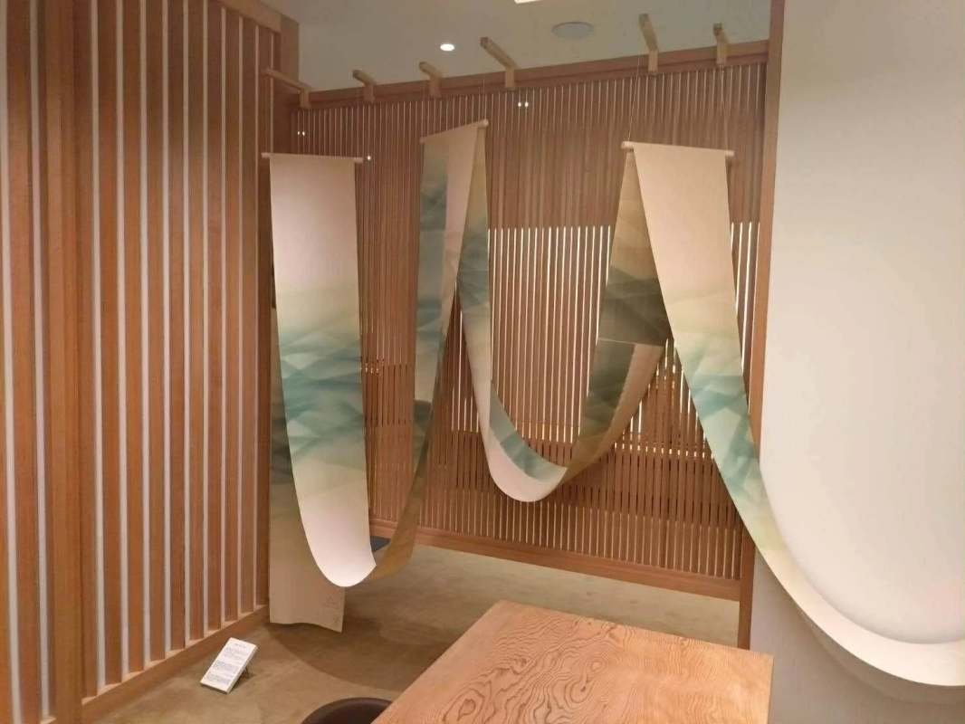 A modern Japanese-style room with wooden lattice walls and gradient fabric art hanging from the ceiling