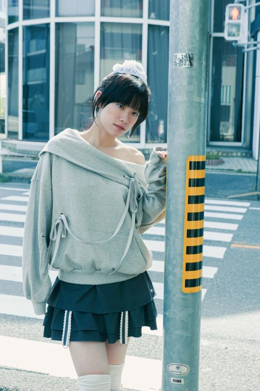 Model in street fashion with off-shoulder top and pleated skirt