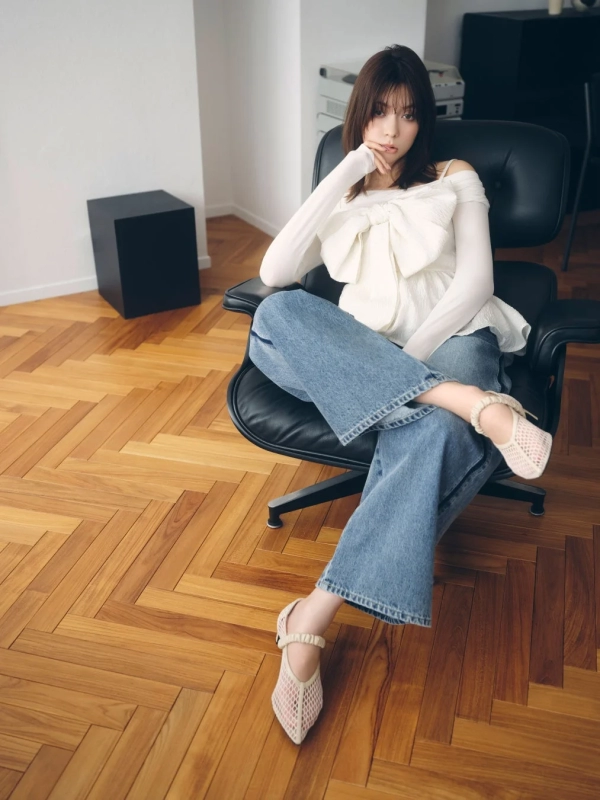 Arisa Yagi in a white off-shoulder ribbon top and wide denim pants, sitting on a chair