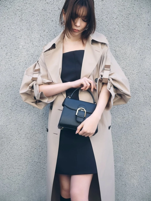Arisa Yagi in a voluminous beige trench coat and black mini dress