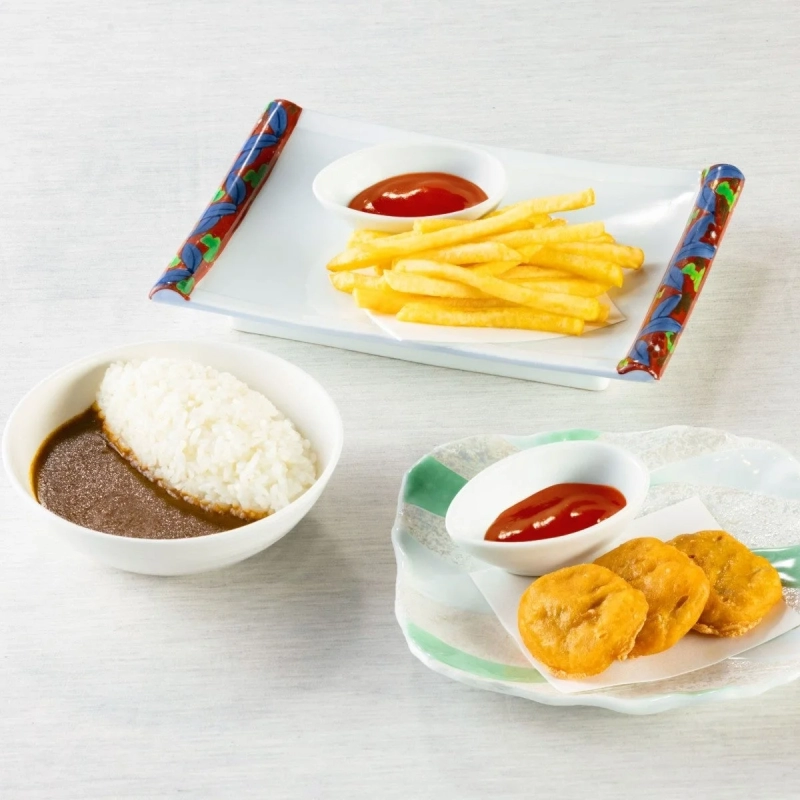A delicious set meal featuring curry rice, golden fried potatoes, and crispy chicken nuggets, served with ketchup on a white table.