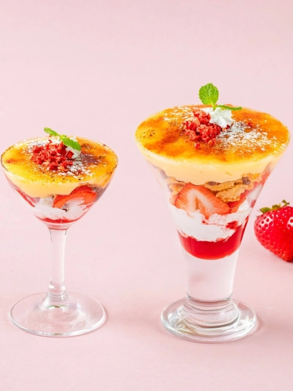 A vibrant display of various parfaits and desserts, featuring strawberries, ice cream, fruits, matcha, and traditional Japanese sweets.