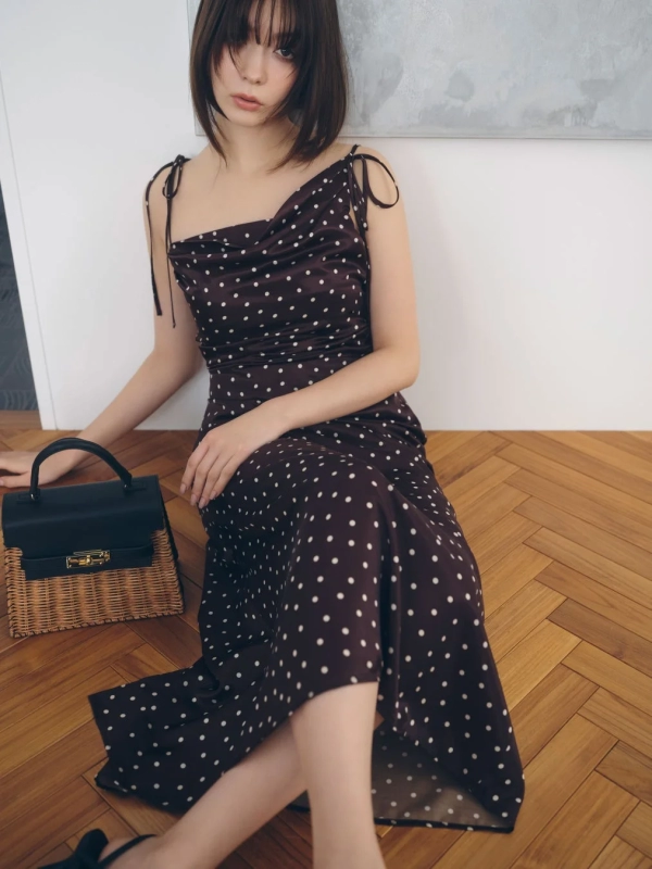 Arisa Yagi in a brown polka dot slip dress with a woven bag