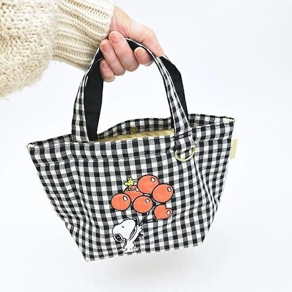 Tote bag held in hand for size comparison