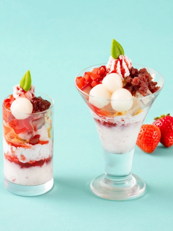 Two beautiful Japanese-style parfaits with layers of strawberries, shiratama, red bean paste, and cream, set against a mint green background.