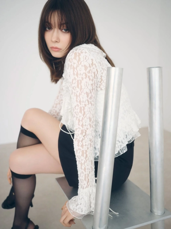 Arisa Yagi in a white lace blouse and black shorts, sitting elegantly