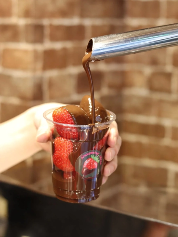 Chocolate being poured over strawberries