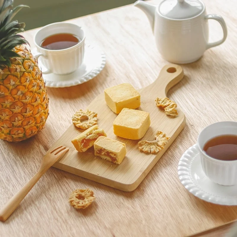 Pineapples and pineapple cakes on a wooden board