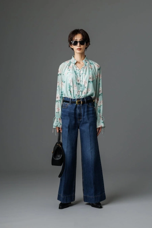Model in a floral blouse and wide denim pants