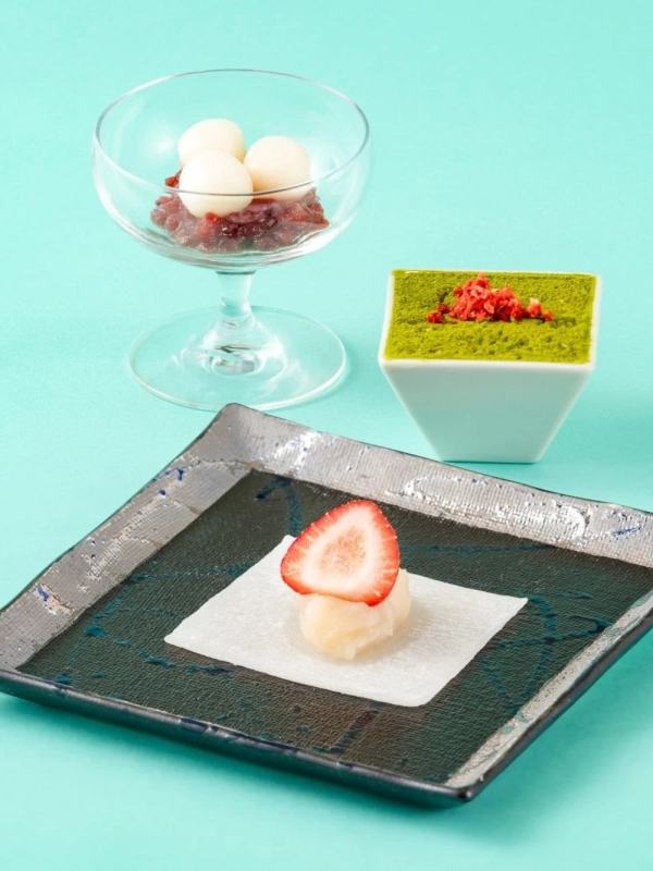 A delightful arrangement of three Japanese sweets: strawberry daifuku, a matcha dessert, and shiratama dango with red bean paste.