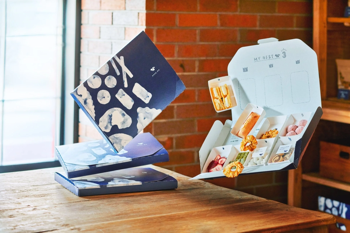 An elegant gift box filled with various snacks, dried fruits, and baked goods, arranged on a wooden table.
