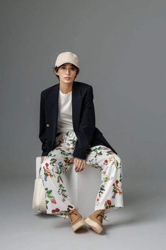 Model in a jacket, floral pants, and cap