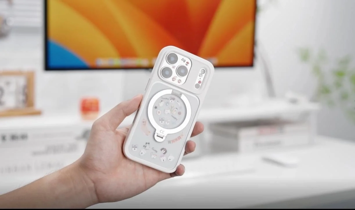 A hand holding a white smartphone case with a transparent back, showing customization with a sticker