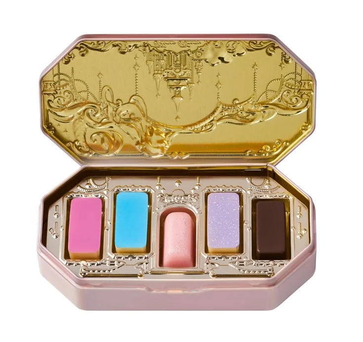 A pink and gold cosmetic palette with five colorful sections, featuring intricate designs.