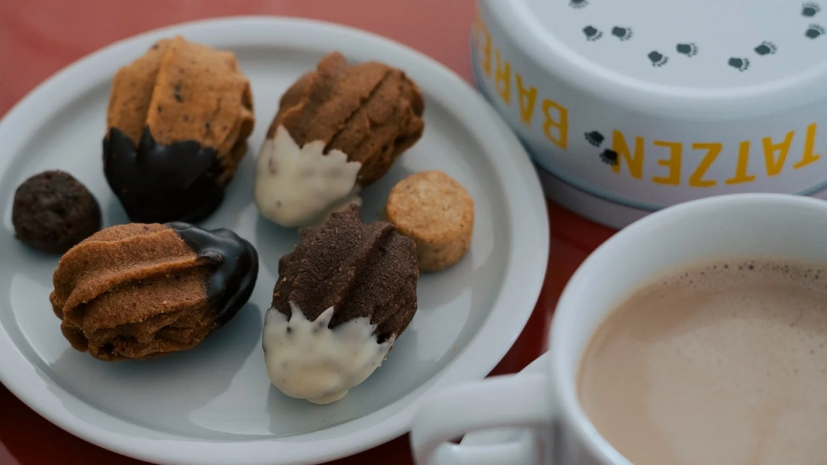 Assortment of Bärenpratzen cookies on a white plate with a bear paw design tin