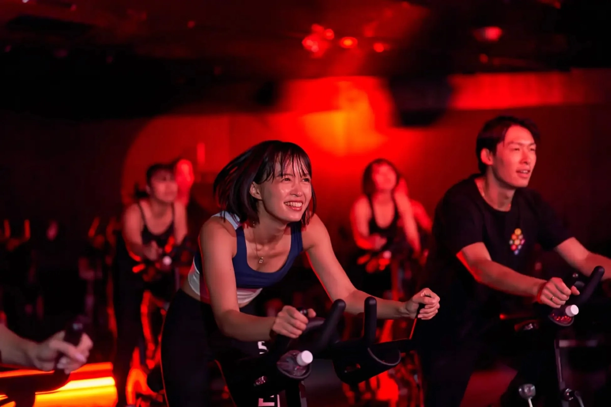 People cycling in a dark fitness studio with red lighting