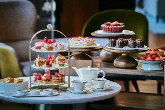A beautifully arranged afternoon tea spread featuring various strawberry-themed desserts, including mini cakes, tarts, and other pastries, set in an elegant dining environment.