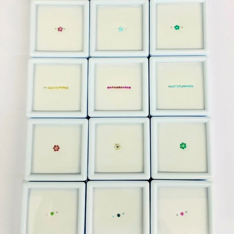 Collection of small, colorful gemstones in white cases
