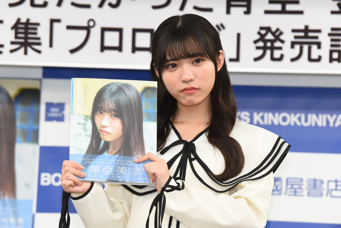 Ami Kanazawa holding the photobook with a serious expression