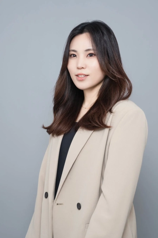 A portrait of Shiho Kariu, Representative Director of Lecture Co., Ltd., smiling gently in a beige jacket against a grey background.