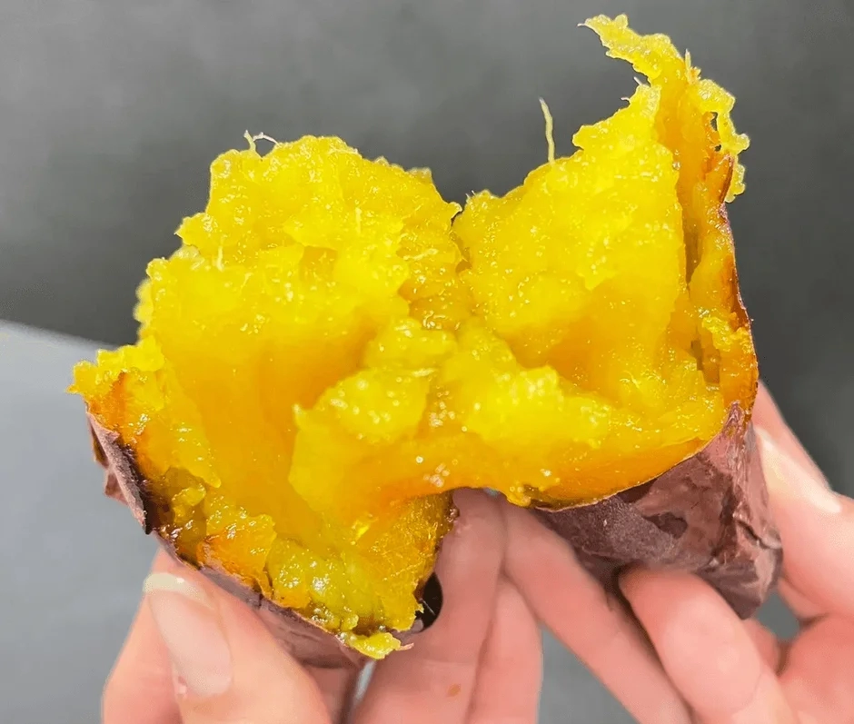 A warm, split roasted sweet potato revealing its moist, yellow interior