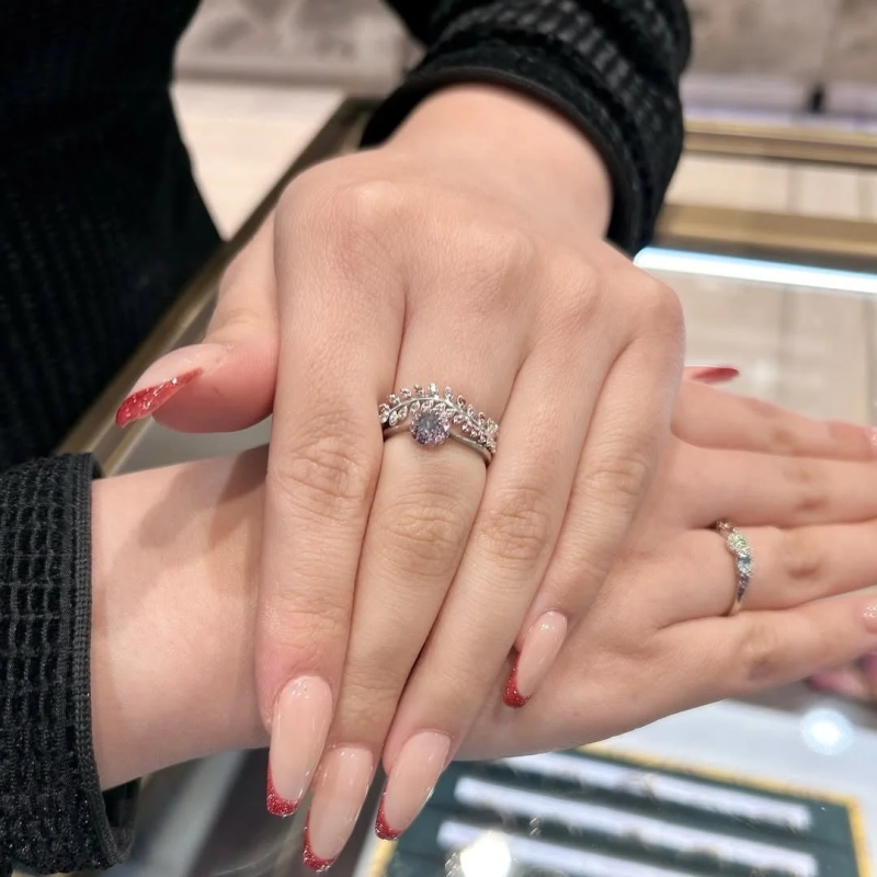 Hand wearing a leaf-motif ring with a pink stone