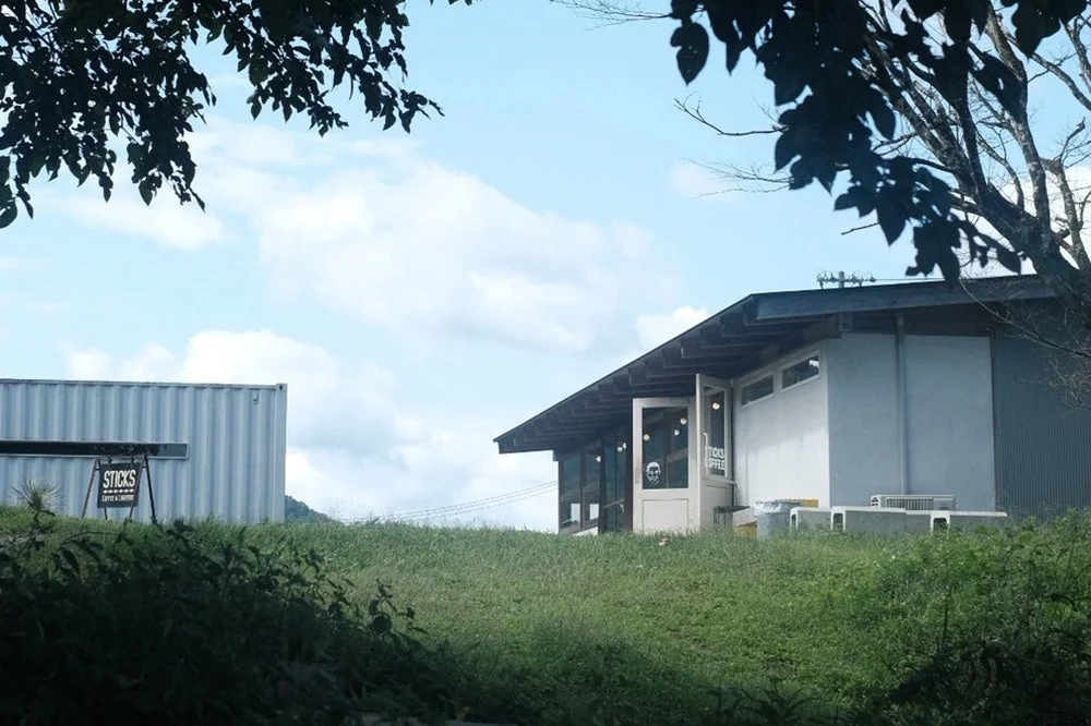 Outdoor view of Sticks Coffee shop with a container house against a blue sky